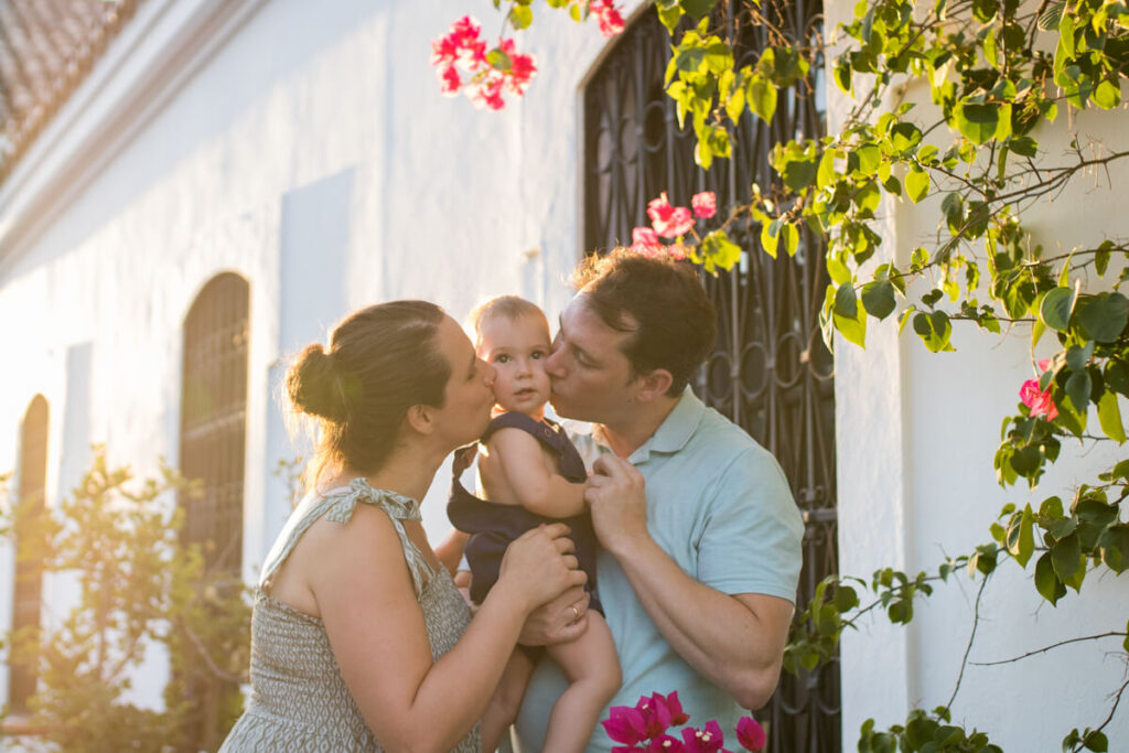 papá y mamá besando a su bebé